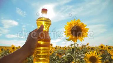 农夫手里拿着一瓶塑料葵花籽油，阳光洒在他的手里。 慢动作视频。 蓝天背景